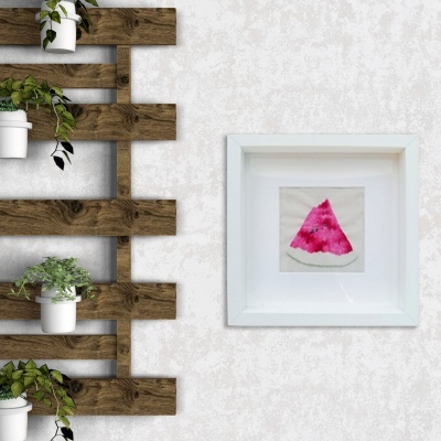 Estrutura de madeira com vasos brancos e quadro com pintura de melancia numa parede cinzenta.