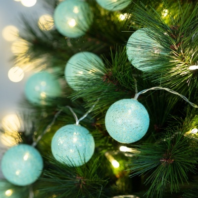 Bolas azuis turquesa em cordão de luzes numa árvore de Natal