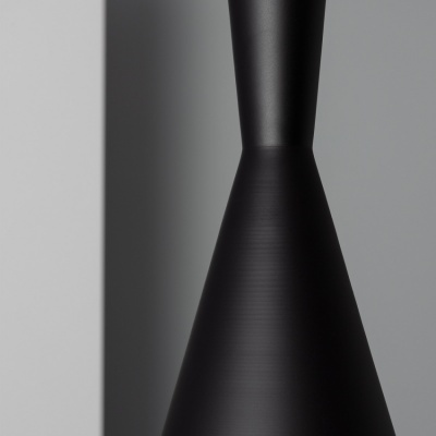 Objeto metálico preto cónico contra fundo cinzento