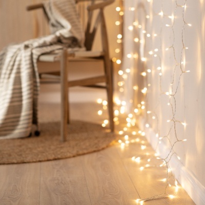 Cordão de luzes LED branco decorativo junto a cadeira com manta às riscas