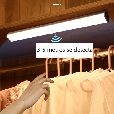 Luz LED montada com sensor acima de cabides com roupas claras
