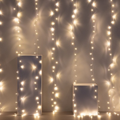 Cordões de luzes LED pendurados em fundo neutro com duas plataformas brancas