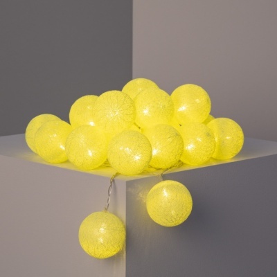 Luzes decorativas em bolas amarelas de tecido iluminadas sobre superfície branca
