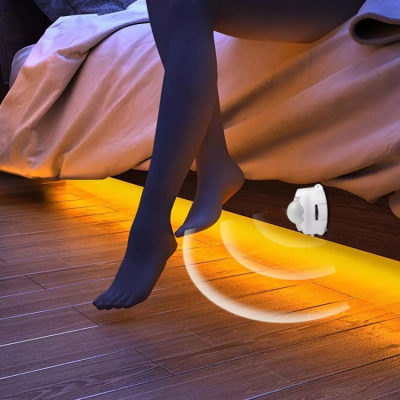 Dispositivo branco sob cama com luz amarela e pernas com meia-calça preta pendendo da cama