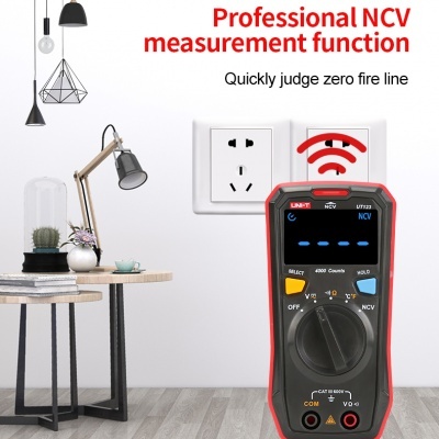 Multímetro digital preto e vermelho junto a tomada branca numa parede, em sala moderna com decoração