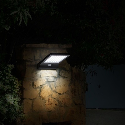 Luz de parede LED exterior instalada em parede de pedra à noite.