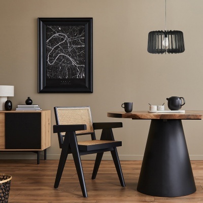 Sala de jantar com cadeira de madeira e rattan, mesa redonda, candeeiro pendente preto, móvel baixo e quadro em moldura preta.