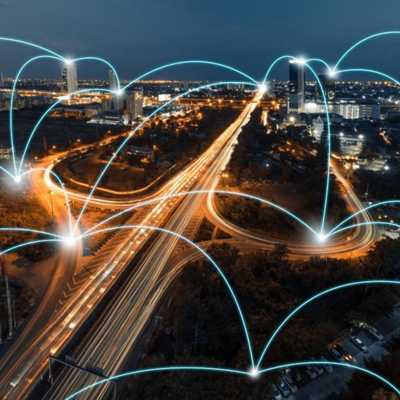 Vista aérea noturna de uma autoestrada urbana com linhas azuis luminosas representando conexões digitais