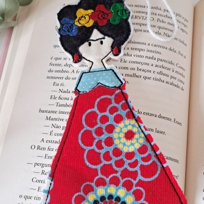 Marcador de livros tecido com figura feminina colorida sobre livro aberto