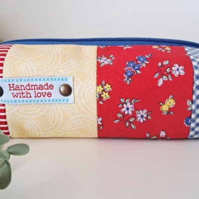 Estojo patchwork com padrões coloridos e etiqueta 'Handmade with love'