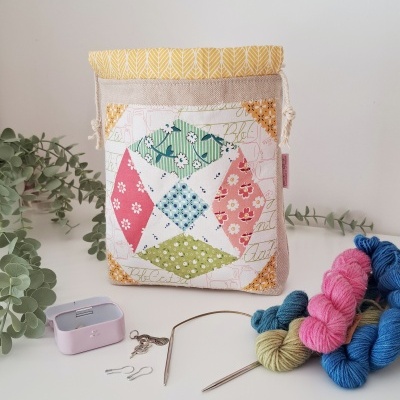 Bolsa de tecido patchwork colorido, novelos de lã e acessórios de tricô