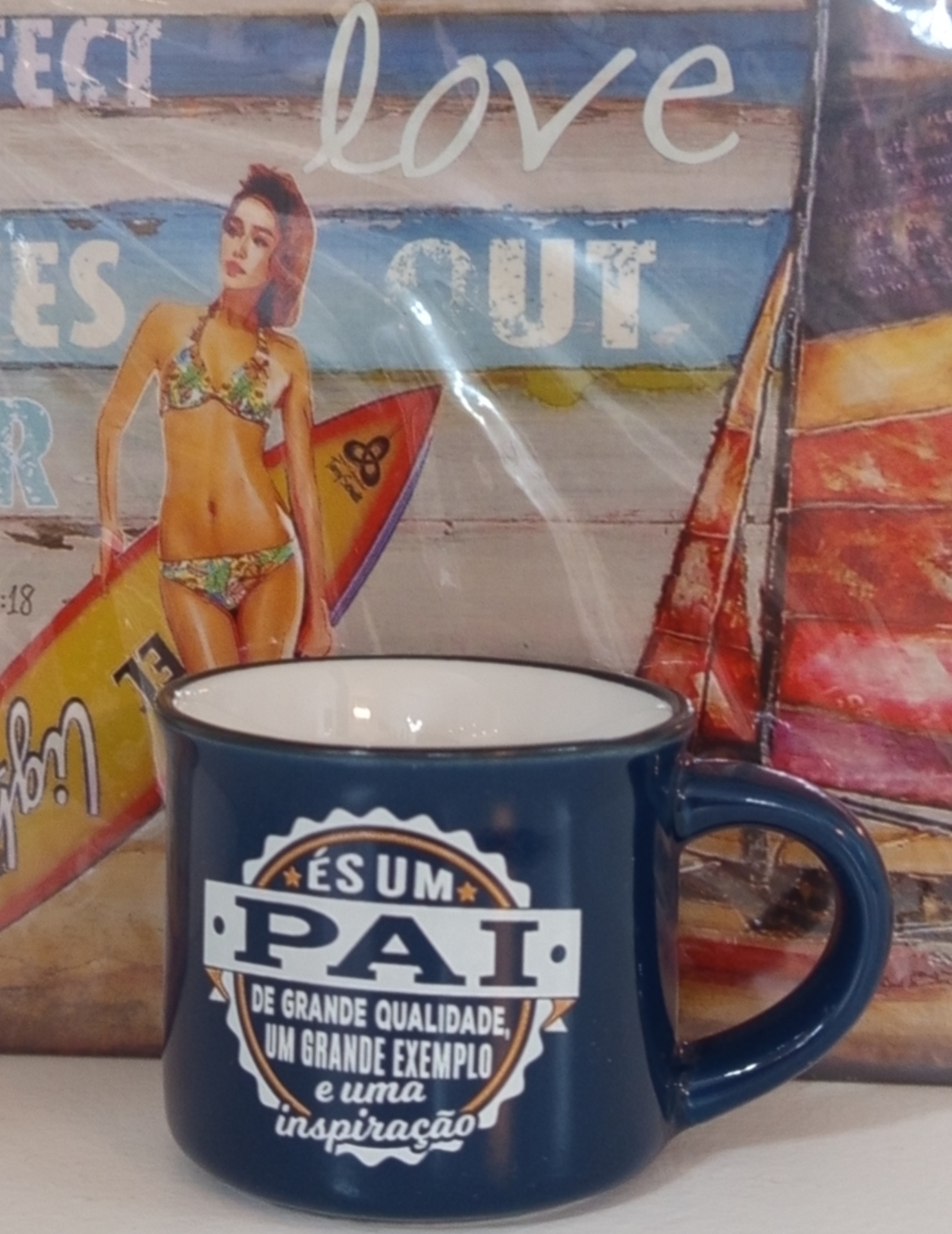 Caneca azul escura com texto em português e imagem de mulher de bikini ao fundo
