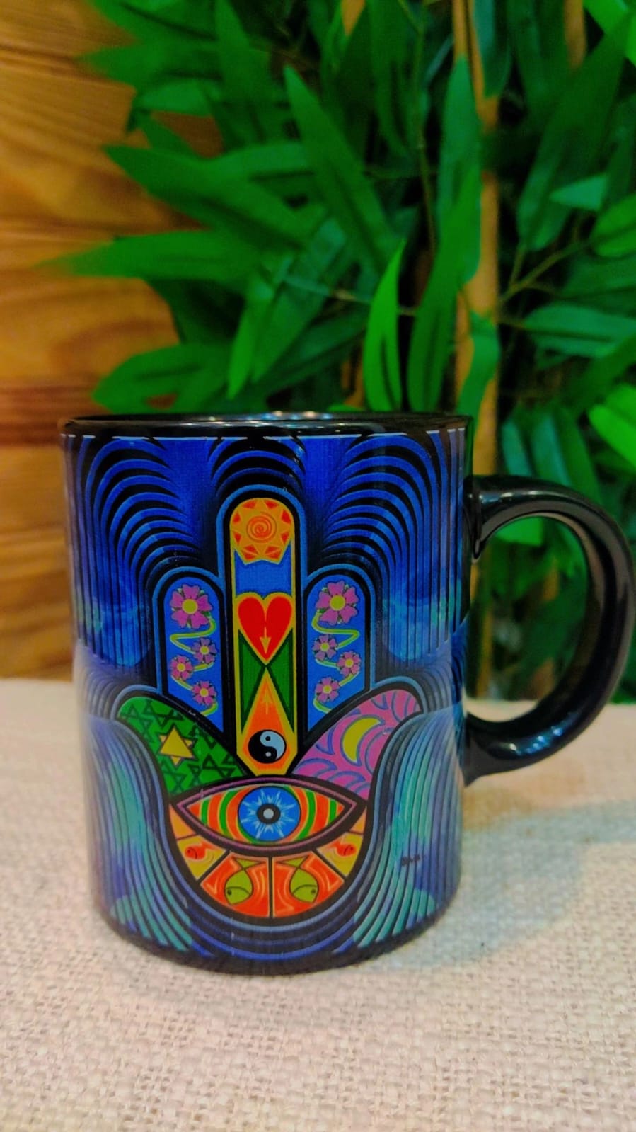 Caneca preta com padrão colorido da mão de Hamsá e olho azul