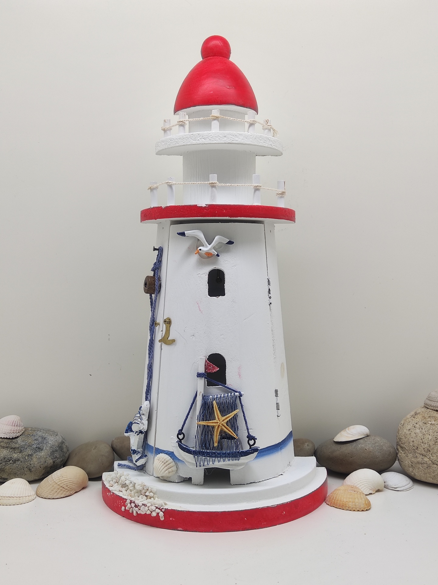 Fanal decorativo em madeira branca e vermelha com detalhes azul, estrela-do-mar e gaivota entre conchas e pedras