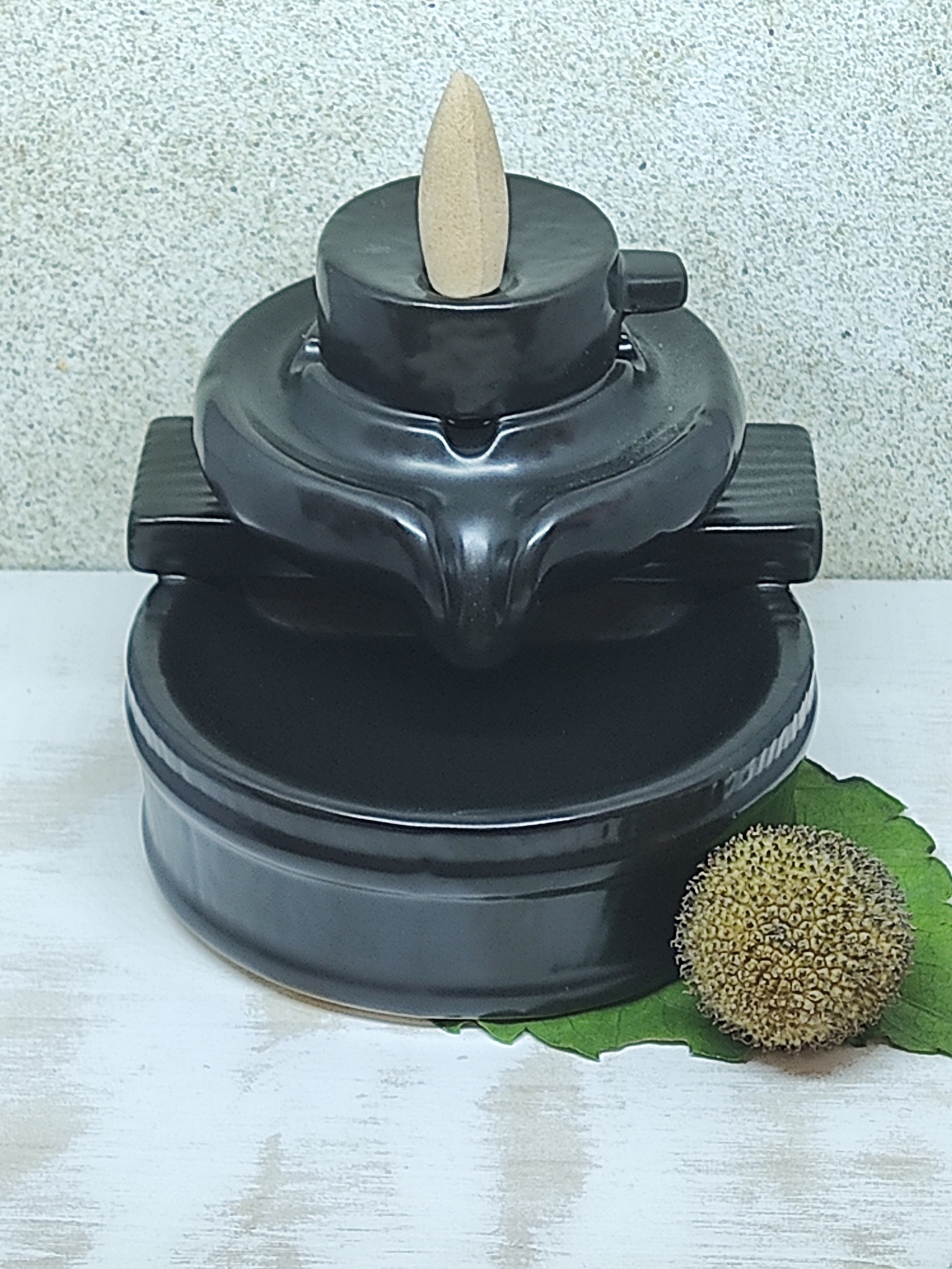 Incensário preto em cerâmica com suporte para cone de incenso e detalhes verdes ao lado