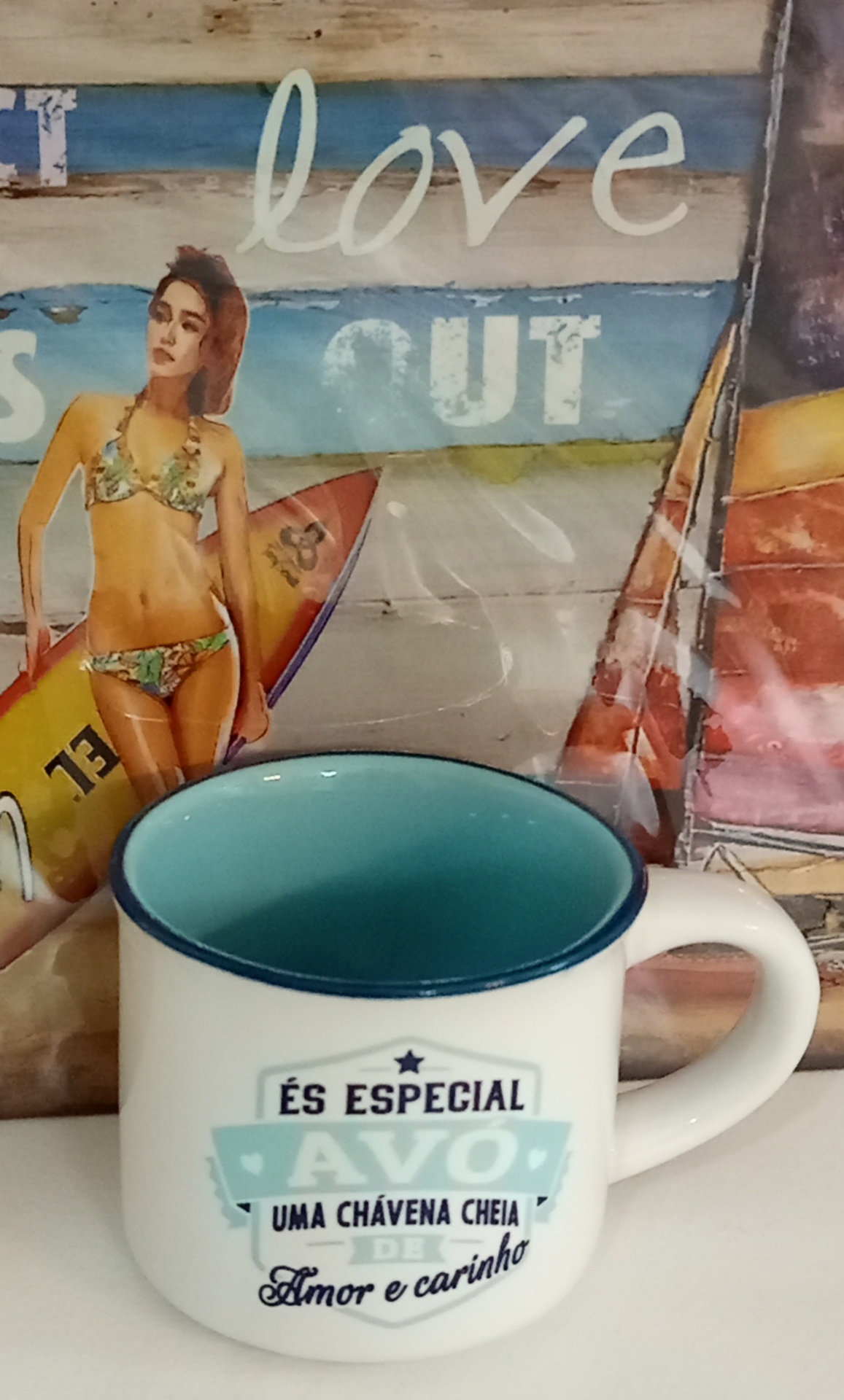 Caneca branca com interior azul turquesa e texto especial para avó, sobre fundo com mulher de biquíni e prancha de surf