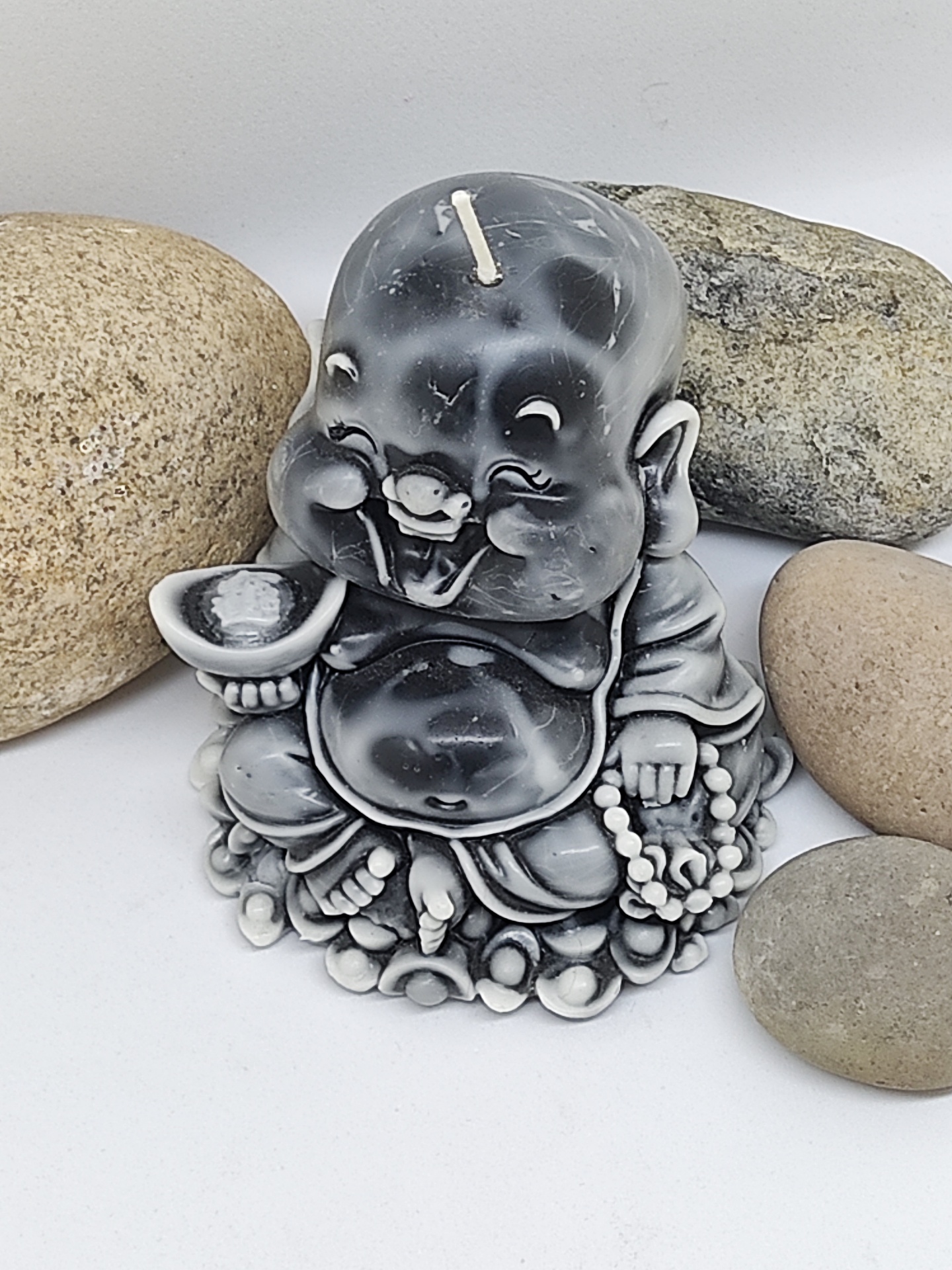 Vela Buda cinza e branco com pedras ao redor