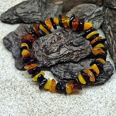Pulseira de pedras de âmbar em tons castanho, amarelo e preto sobre cascas de árvore