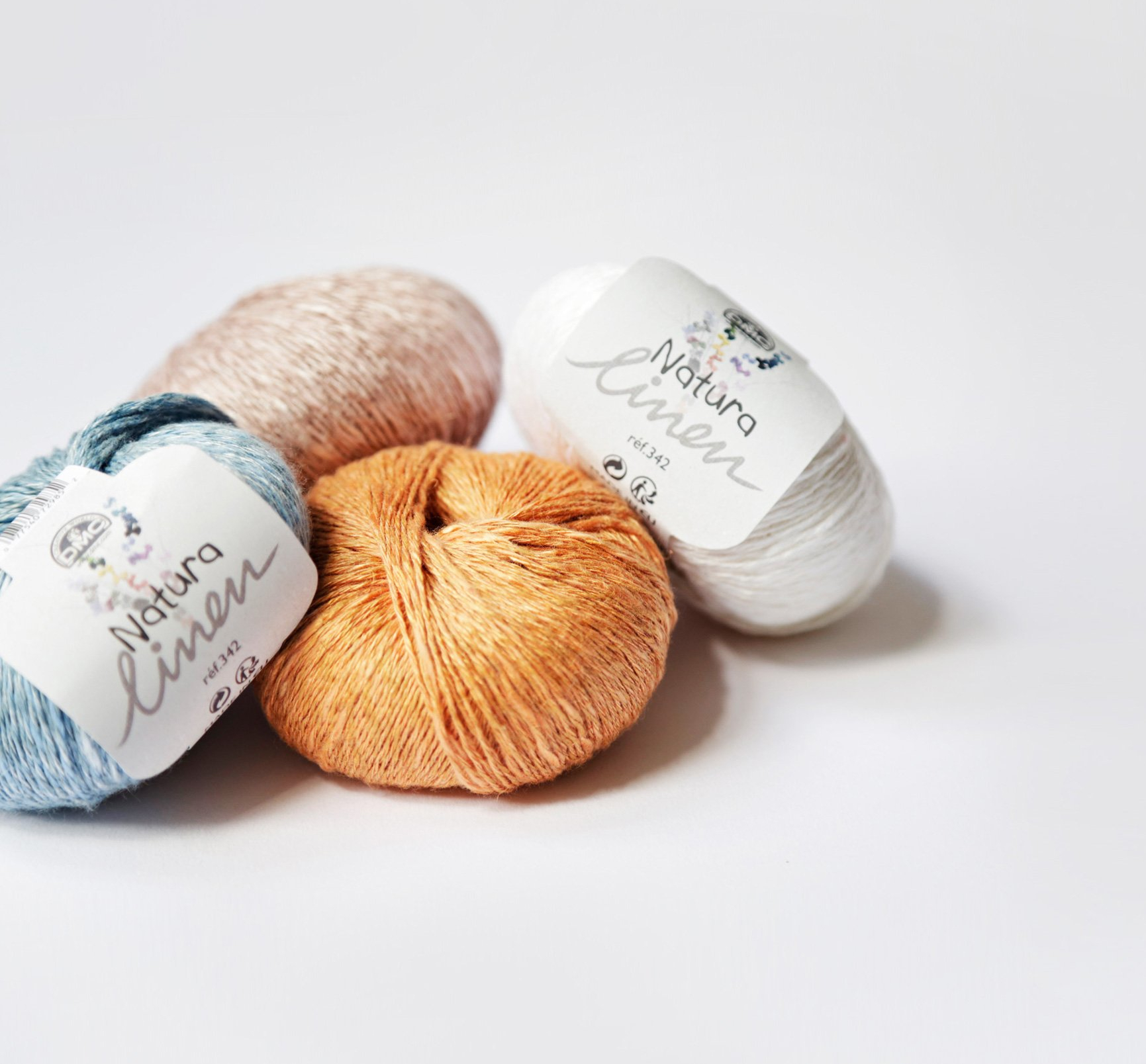 Quatro novelos de fio Natura Linen da Pingouin em várias cores sobre fundo branco