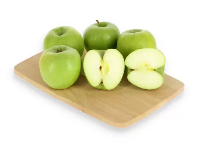 Seis maçãs verdes em tábua de madeira, duas cortadas ao meio mostrando interior branco