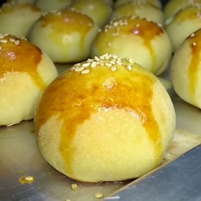 Pães redondos dourados com gergelim numa bandeja metálica