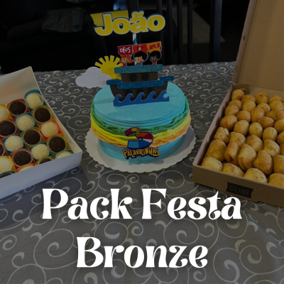 Mesa com bolo decorado de aniversário e caixas de brigadeiros e salgadinhos para festa