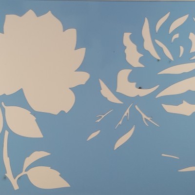 Stencil azul com padrões de flores e folhas numa embalagem preta com logótipo e texto.