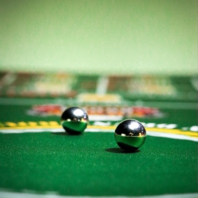Two metallic balls on green felt gaming table with white and yellow markings