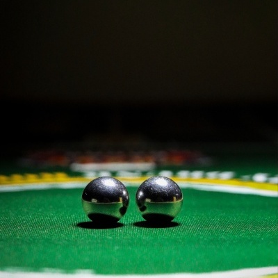 Two small metallic balls on a green felt gaming table with yellow and white markings