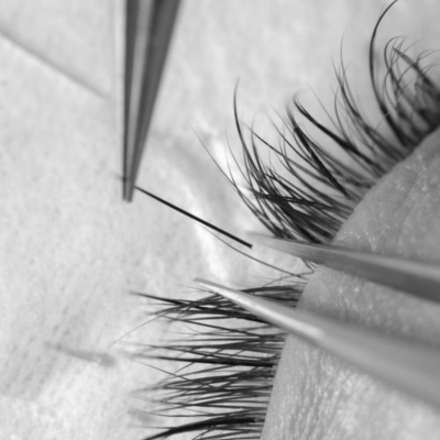 Close-up de pestanas com pinças a aplicar pestana artificial