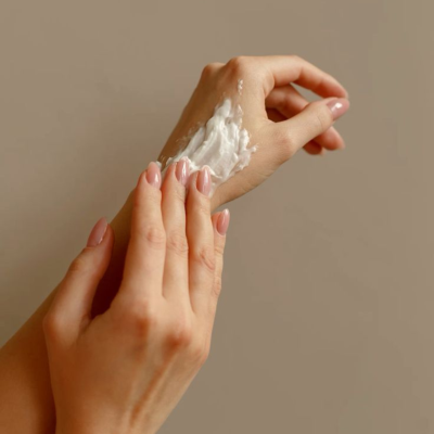 Mãos femininas a aplicar creme branco na pele