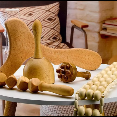 Acessórios de massagem em madeira sobre mesa branca com cadeira e almofada ao fundo.