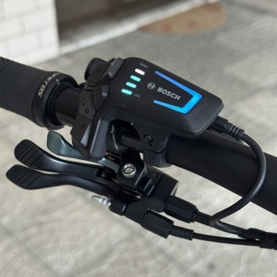 Comando eletrónico Bosch preto com botões e LEDs num guiador de bicicleta preto