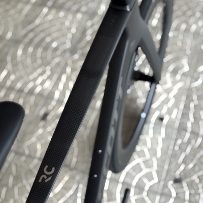 Bicicleta preta de estrada com rodado de disco sólido e inscrição RC no quadro