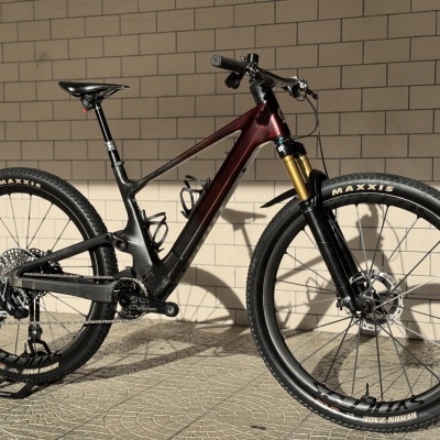 Bicicleta de montanha com quadro vermelho e preto encostada numa parede de azulejos bege