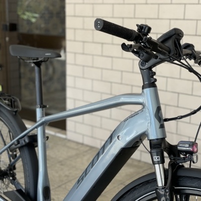 Bicicleta elétrica cinzenta encostada a uma parede de azulejos brancos