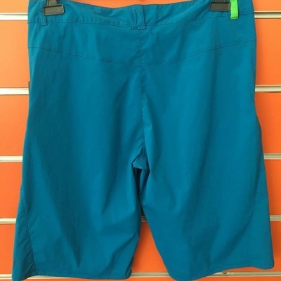 Calções azuis com detalhe verde pendurados num cabide