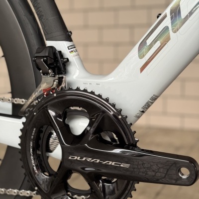 Pedaleira DURA-ACE e quadro de bicicleta branca com detalhes e roda preta.