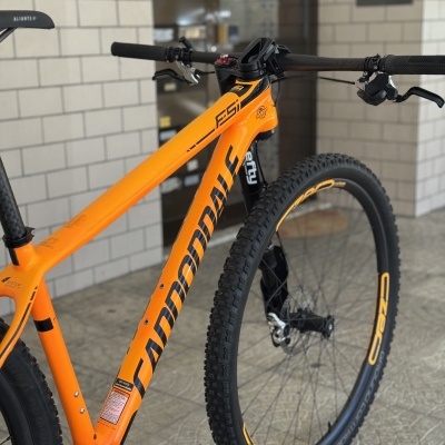 Bicicleta de montanha Cannondale F-Si laranja com pneus pretos e detalhes amarelos