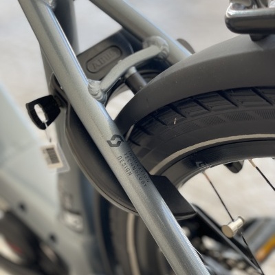 Detalhe da parte traseira do quadro de bicicleta cinzenta metálica com texto impresso e pneu preto