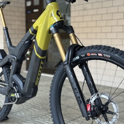 Bicicleta elétrica de montanha amarelo e cinza com suspensão dianteira dourada e travão a disco