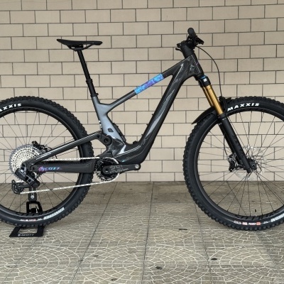 bicicleta de montanha elétrica cinza escuro com suspensão dourada e pneus Maxxis