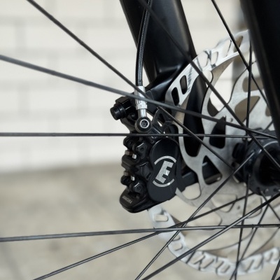 Sistema de travagem a disco de bicicleta com disco prateado e pinça preta com logótipo branco