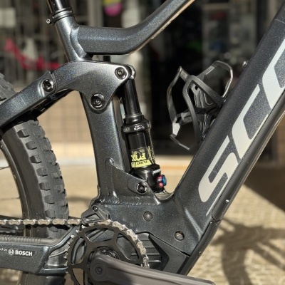 Bicicleta de montanha elétrica cinzenta com amortecedor traseiro FOX e suporte de garrafa