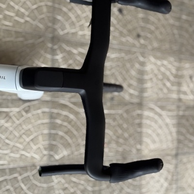 Guiador de bicicleta preto e quadro branco sobre chão de pedras cinzentas