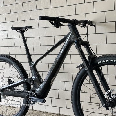 Bicicleta elétrica de montanha preta apoiada numa parede de azulejos brancos