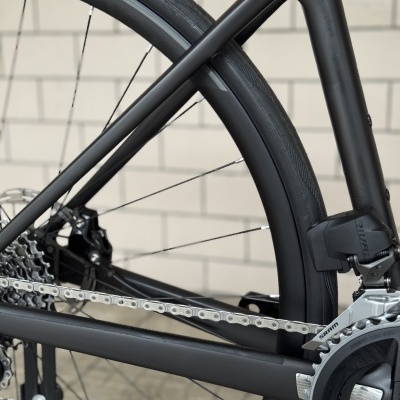 Roda traseira de bicicleta preta com corrente e quadro em carbono fosco