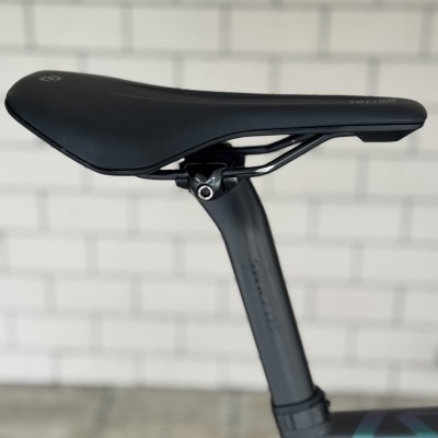 Selim de bicicleta preto montado num quadro azul escuro de bicicleta.