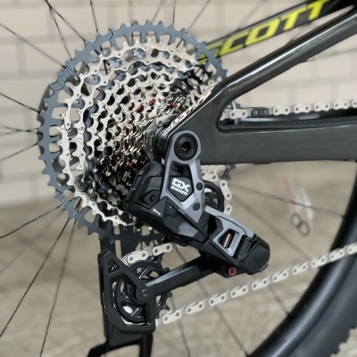 Roda traseira de bicicleta com cassete metálico prateado e desviador preto GX no quadro cinza SCOTT