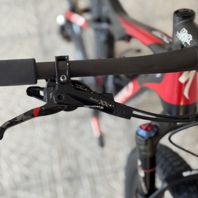 Punho e manete de travão Avid de bicicleta preta com detalhes vermelhos e preto no quadro, suspensão frontal e pneu de cravos